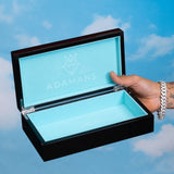 Premium Adamans Box luxury jewelry storage box with turquoise interior and black polished exterior held against a sky background
