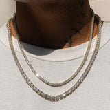 3mm and 5mm gold tennis chain bundle on neck, layered style.