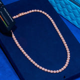 Rose gold micro clustered tennis chain with hand-set simulated diamonds on blue background