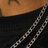 4mm Figaro chain in white gold on black fabric background.