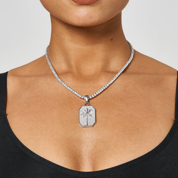 Palm tree pendant in white gold with diamond simulants on a silver chain necklace worn by a woman