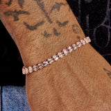 4mm moissanite broken heart bracelet in rose gold on wrist with tattoos and denim background