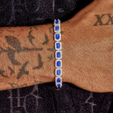 Men's wrist wearing sapphire cushion cut tennis bracelet in white gold with vivid blue sapphires