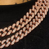 Close-up of a 13mm rose gold Moissanite Cuban chain with sparkling VVS1 clarity stones on black fabric