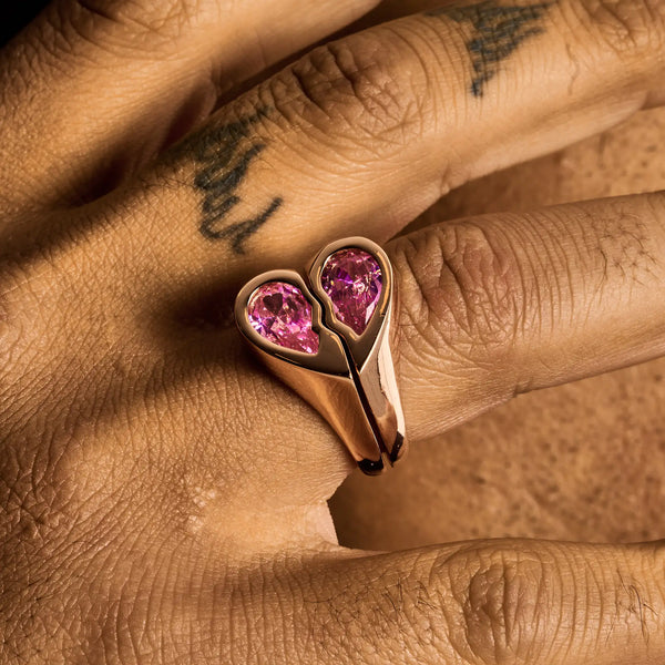 Rose gold broken heart ring with pink heart-shaped stones on hand