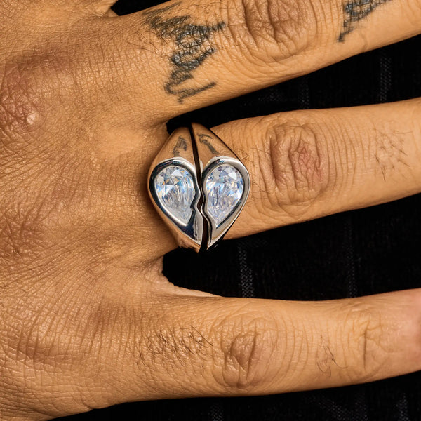 White gold broken heart ring with diamond simulants on finger, symbolizing bold elegance