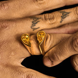 Close-up of gold Broken Heart Ring with yellow gemstone on finger with tattoos