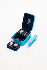 Small blue leather travel jewellery case with stackable suede trays and adjustable strap displaying watches and bracelets