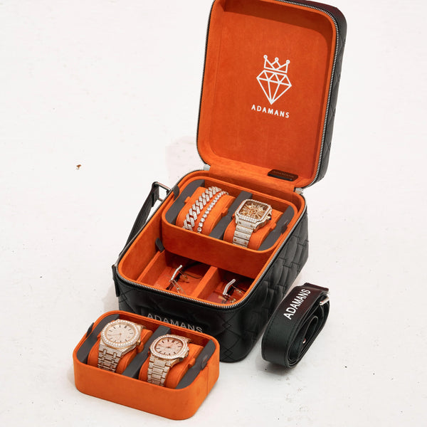 Black leather travel jewellery case with orange suede interior, stackable trays, and adjustable strap for watches and accessories