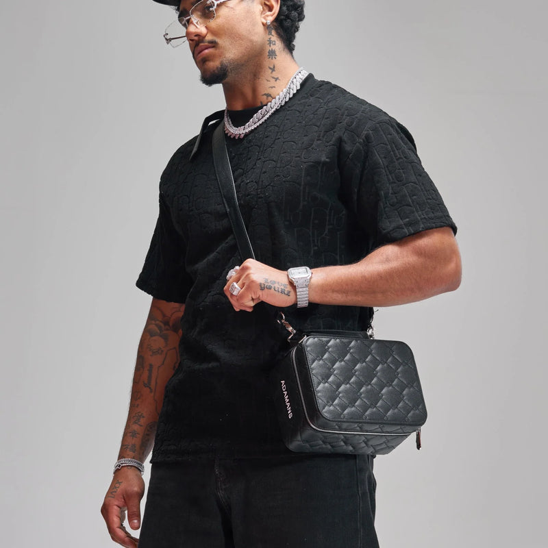 man wearing black top carrying small black leather travel jewellery case with adjustable shoulder strap