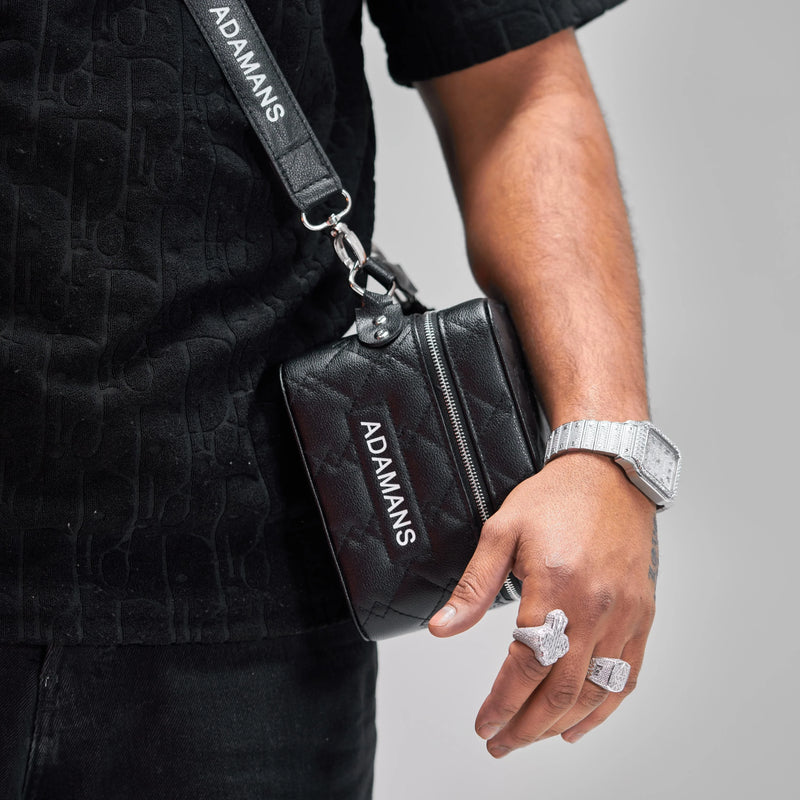 Black leather travel jewellery case with adjustable shoulder strap worn by a person