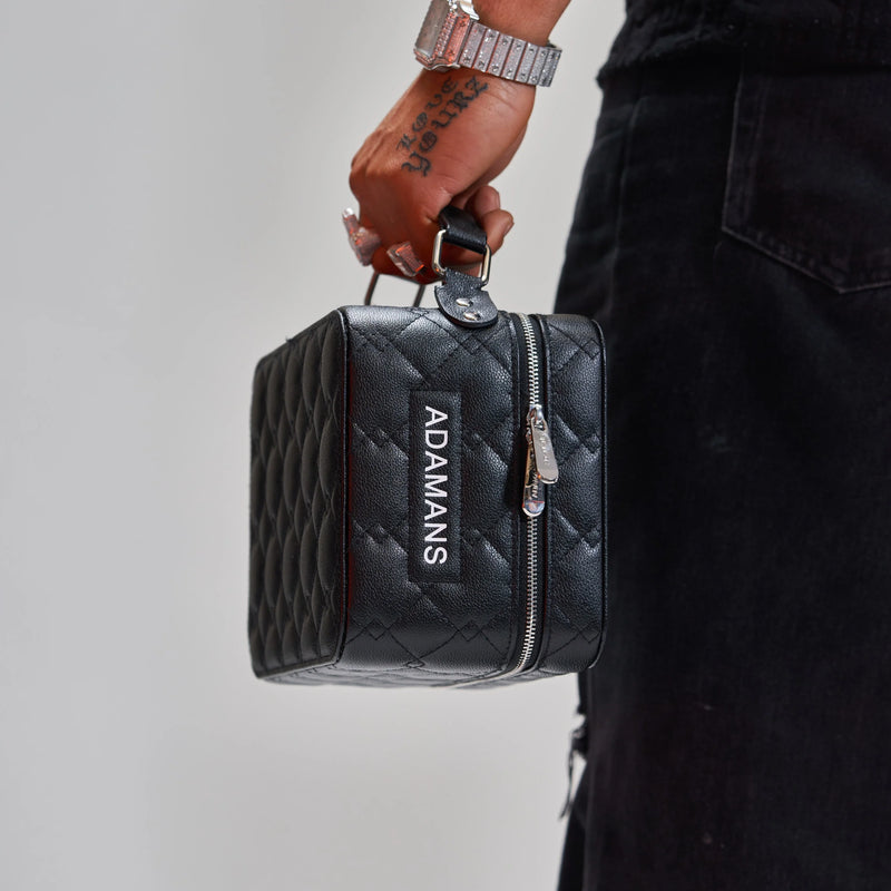 black leather travel jewellery case with quilted pattern and zipper held by hand