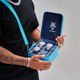 blue small leather travel jewellery case with adjustable strap and watches inside held by a person with tattoos