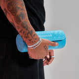 Blue leather travel watch roll by Adamans held in hand with tattooed arm and silver bracelets