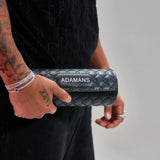 Black leather travel watch roll by Adamans held in hand with quilted design and adjustable strap