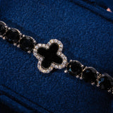 5MM black four leaf clover tennis bracelet in white gold with black stones and diamond accents on blue background