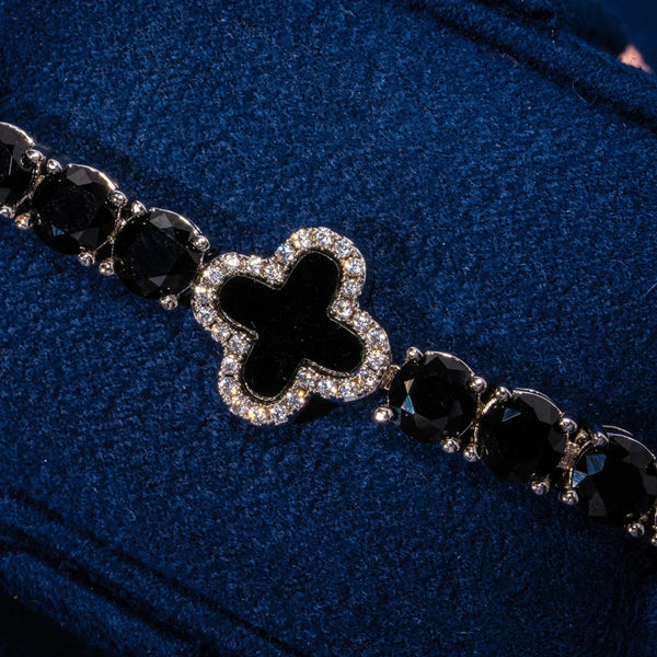 5MM black four leaf clover tennis bracelet in white gold with black stones and diamond accents on blue background