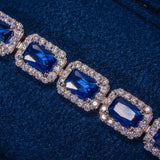 Close-up of sapphire cushion cut tennis bracelet in white gold with blue sapphires surrounded by sparkling diamonds on blue fabric background