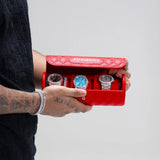Red leather travel watch roll by Adamans holding three watches in a quilted design case