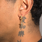 Close-up of gold mini cross earrings iced with VS diamond simulants worn on ear