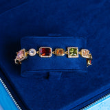 10MM Moissanite multi gemstone bracelet in 18K vermeil with colorful rectangular and square stones on blue velvet background