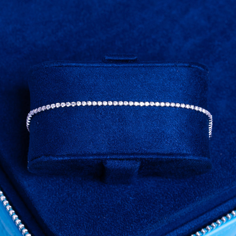 Micro Tennis Bracelet in white gold with 1.5mm round cut diamond simulants, elegant and sparkling on a blue velvet display.