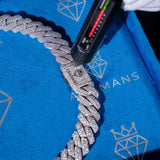 A close-up of a diamond-encrusted Cuban link chain bracelet on a bright blue branded jewelry box, with a black spectrometer held above the chain.