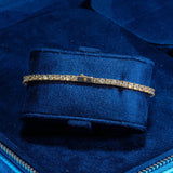 3mm gold tennis bracelet with round cut prong-lifted stones on blue velvet display
