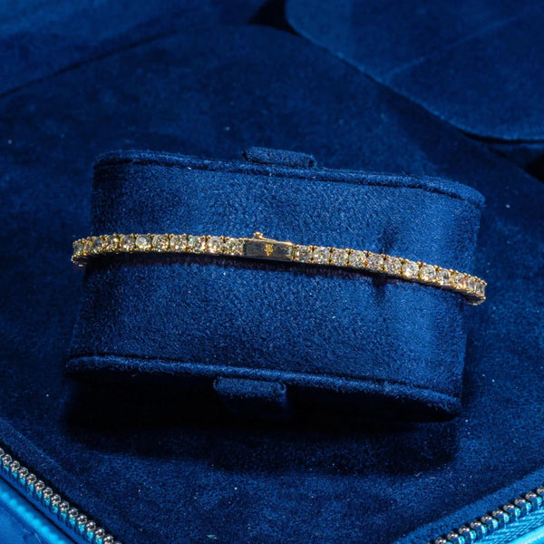 3mm gold tennis bracelet with round cut prong-lifted stones on blue velvet display