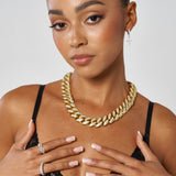 Woman wearing 19mm Iced Cuban Chain gold necklace with diamond simulants on white background