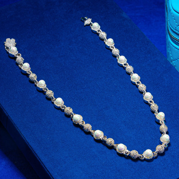 Round bead chain in white gold with prong-lifted stones on a blue background.