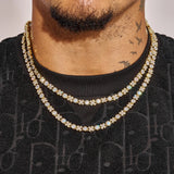 Close-up of a man wearing two gold 5MM XOXO Chains with diamond simulants on a black shirt