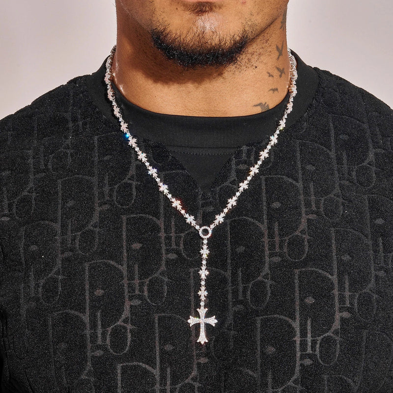 Flared Cross Rosary tennis chain necklace in white gold with radiant stones and bold cross pendant worn on neck