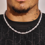 Close-up of 7MM moissanite oval emerald cut tennis chain in 925 silver with white gold plating worn on neck