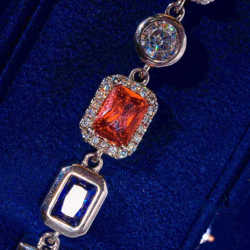 Close-up of 10MM multi gemstone bracelet in white gold featuring hand-set prong-lifted stones with diamond simulants on dark blue background