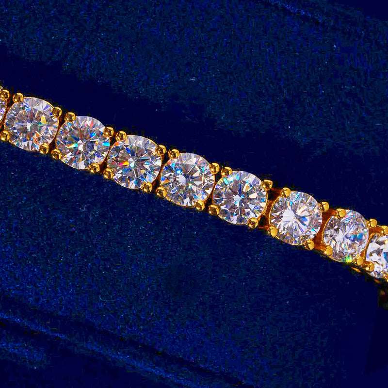 5mm gold tennis bracelet with round cut prong-lifted diamond simulant stones on a dark blue background