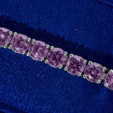 Close-up of 5mm tennis bracelet with purple amethyst stones set in silver prongs on blue background
