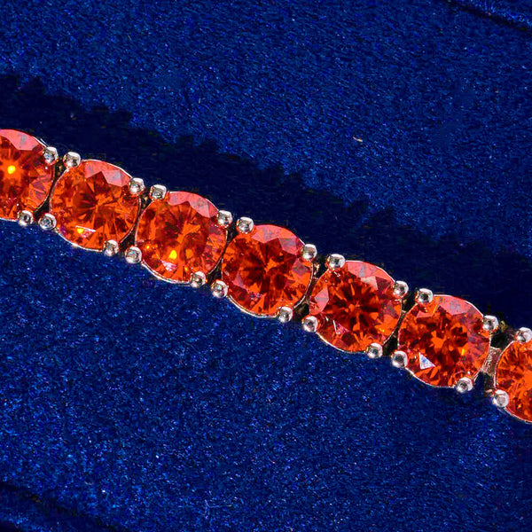 Close-up of 5mm tennis bracelet featuring vibrant red ruby stones on gold setting against blue velvet background