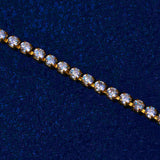 Close-up of gold micro tennis bracelet with round cut diamond simulant stones on dark blue background