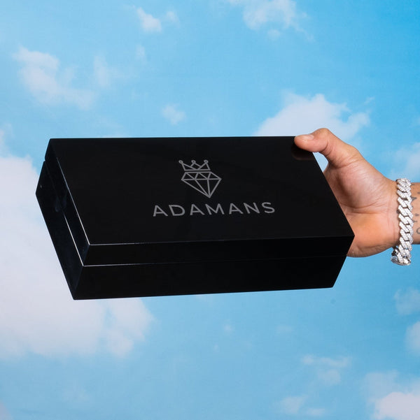 Premium Adamans Box held in hand against a cloudy sky background.